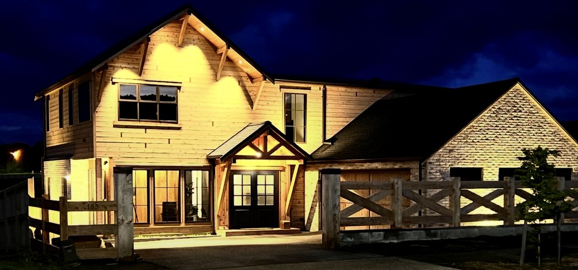 The Timber Residence lit at night, timber and stone elevation under a deep blue sky