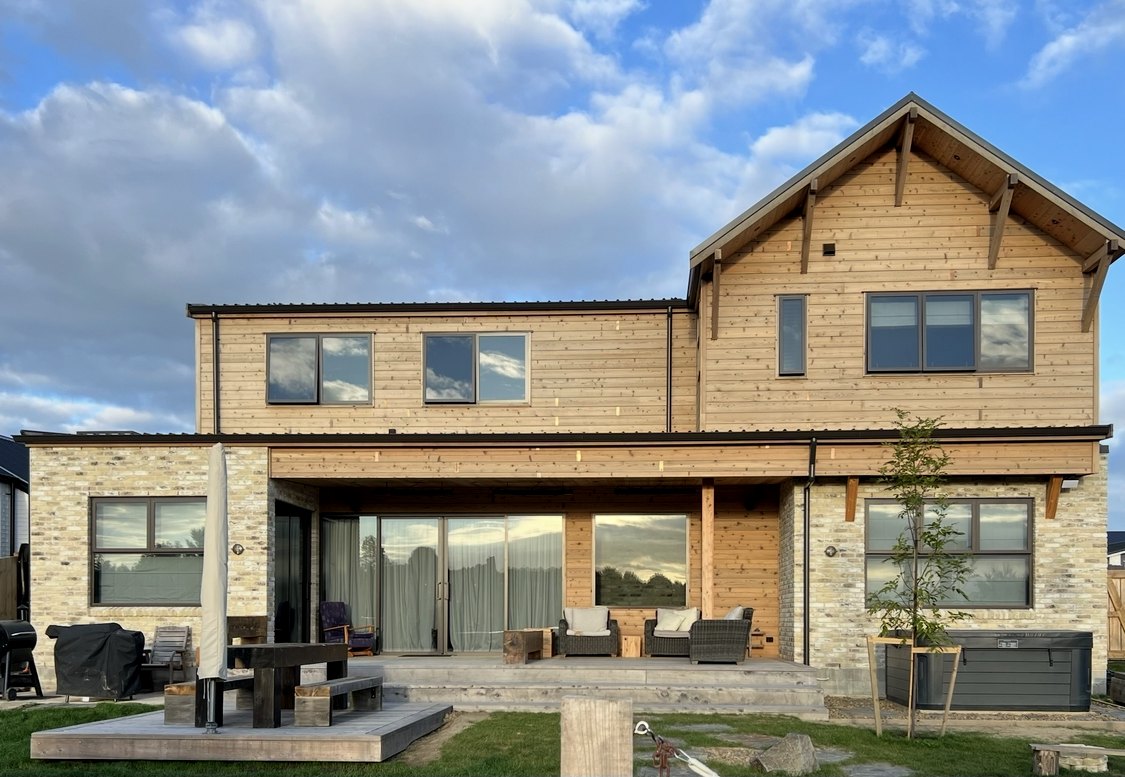 Rear elevation at golden hour, covered outdoor living and deck